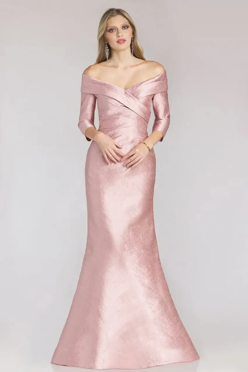 Model is wearing an off-the-shoulder mermaid gown with pleated details, sculpted seams, and a sweetheart neckline.