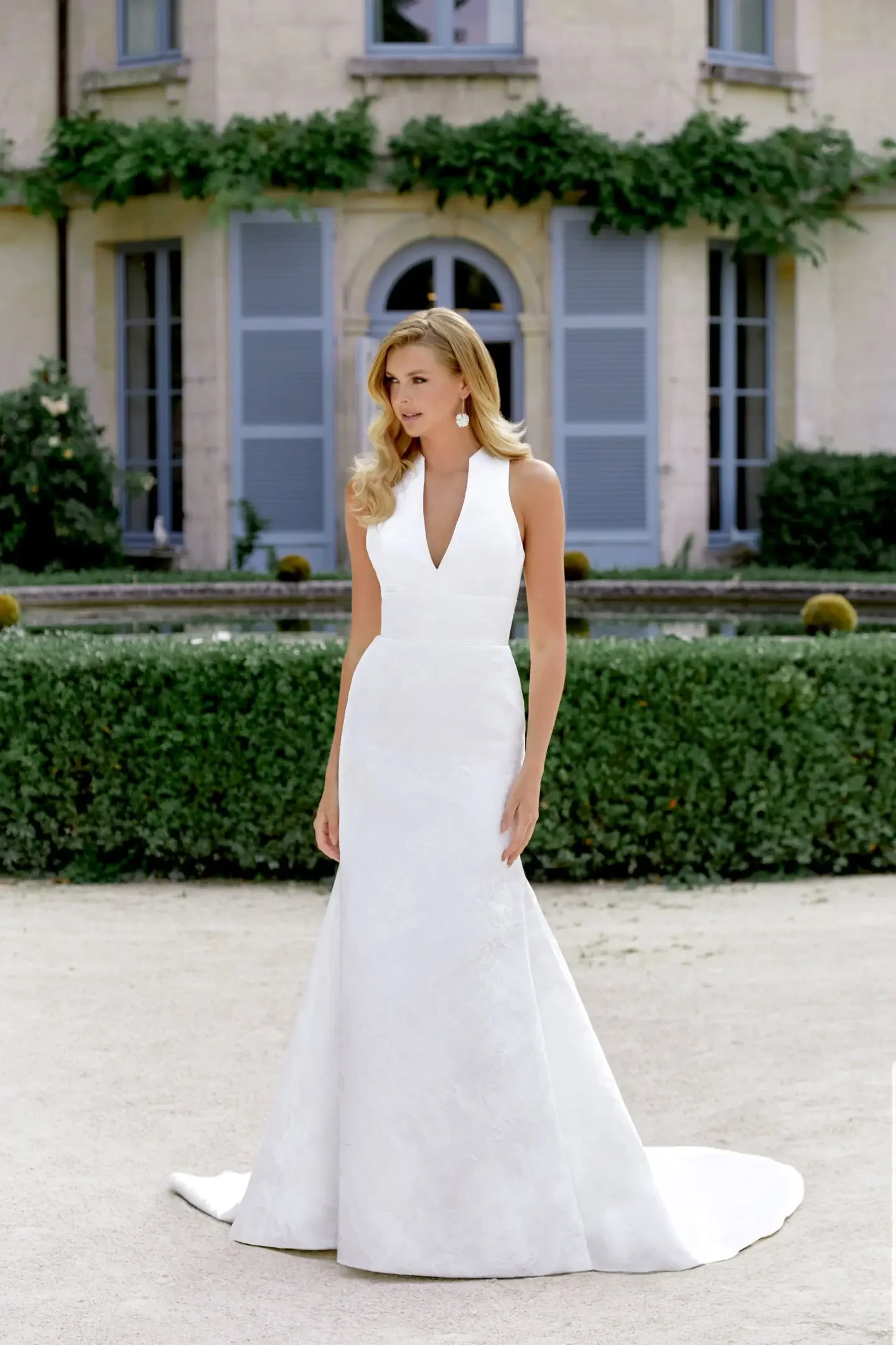 model is wearing a sleeveless wedding dress with an overskirt