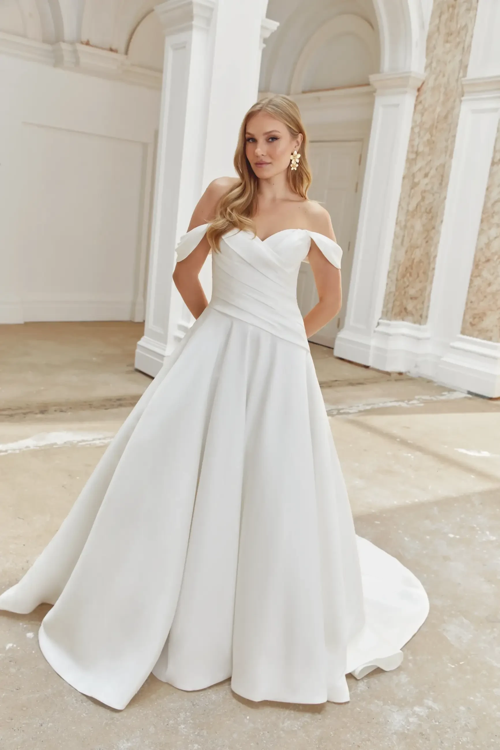 model is wearing an off the shoulder a-line wedding dress