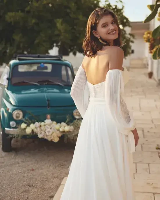 model is wearing an off the shoulder wedding dress with blouson long sleeves