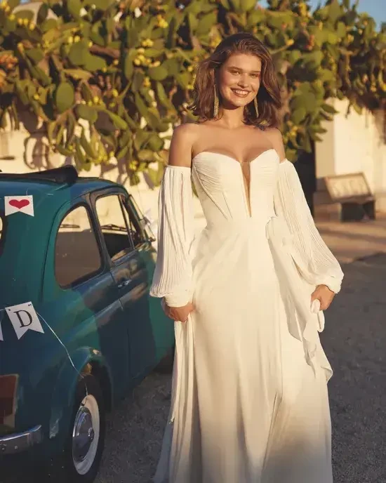 model is wearing an off the shoulder wedding dress with blouson long sleeves