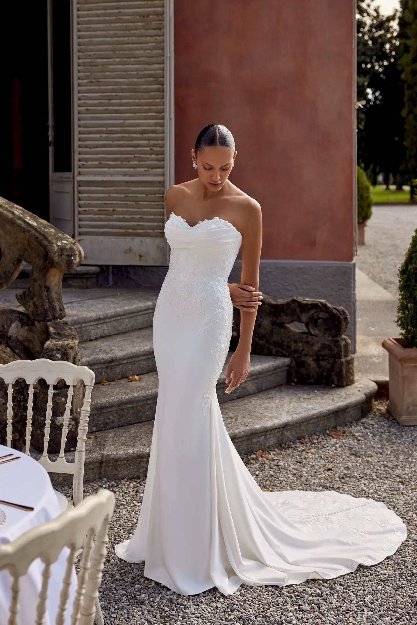 model is wearing a strapless lace fit and flare bridal gown with a train