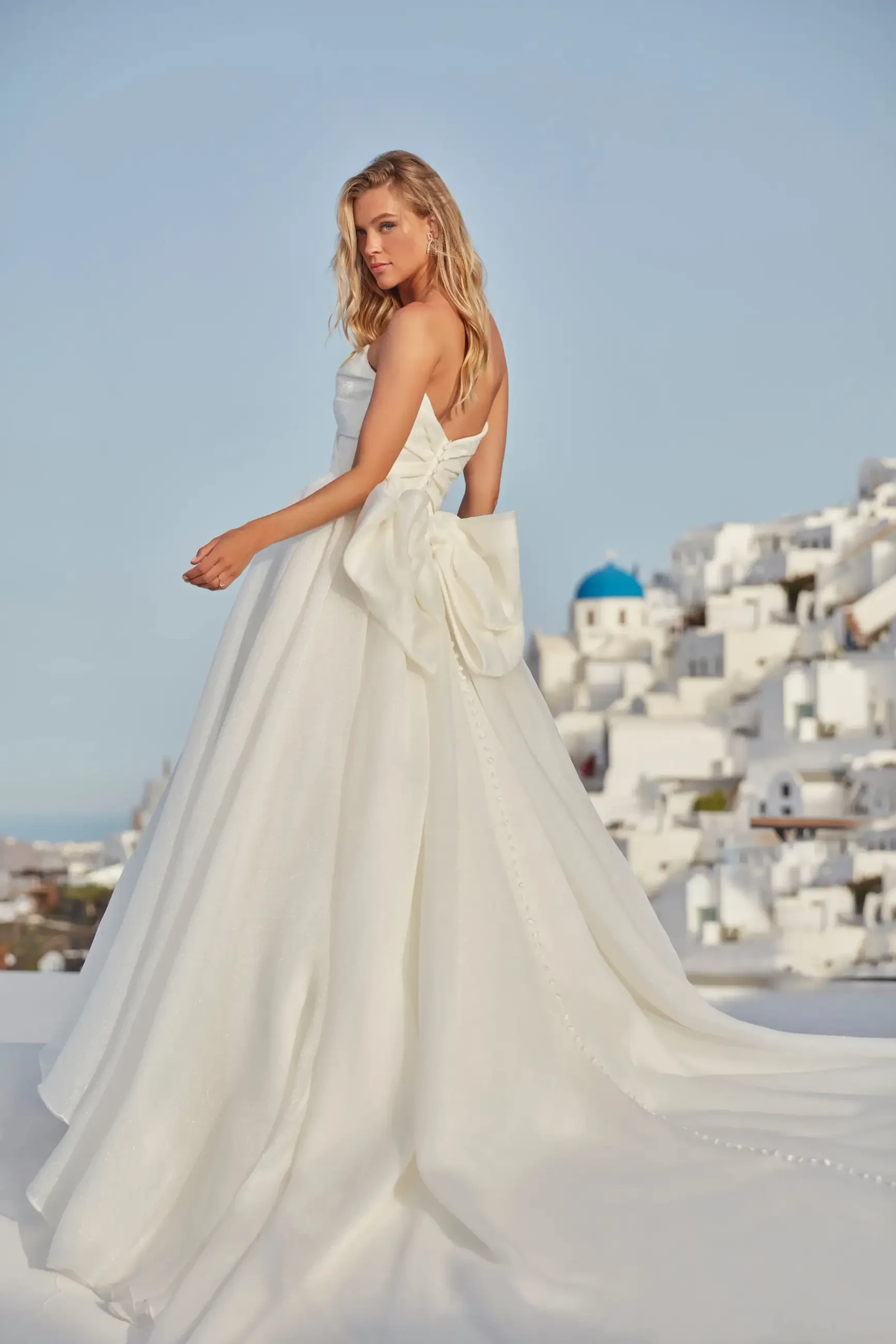 model is wearing an a-line wedding dress with a bow on the back