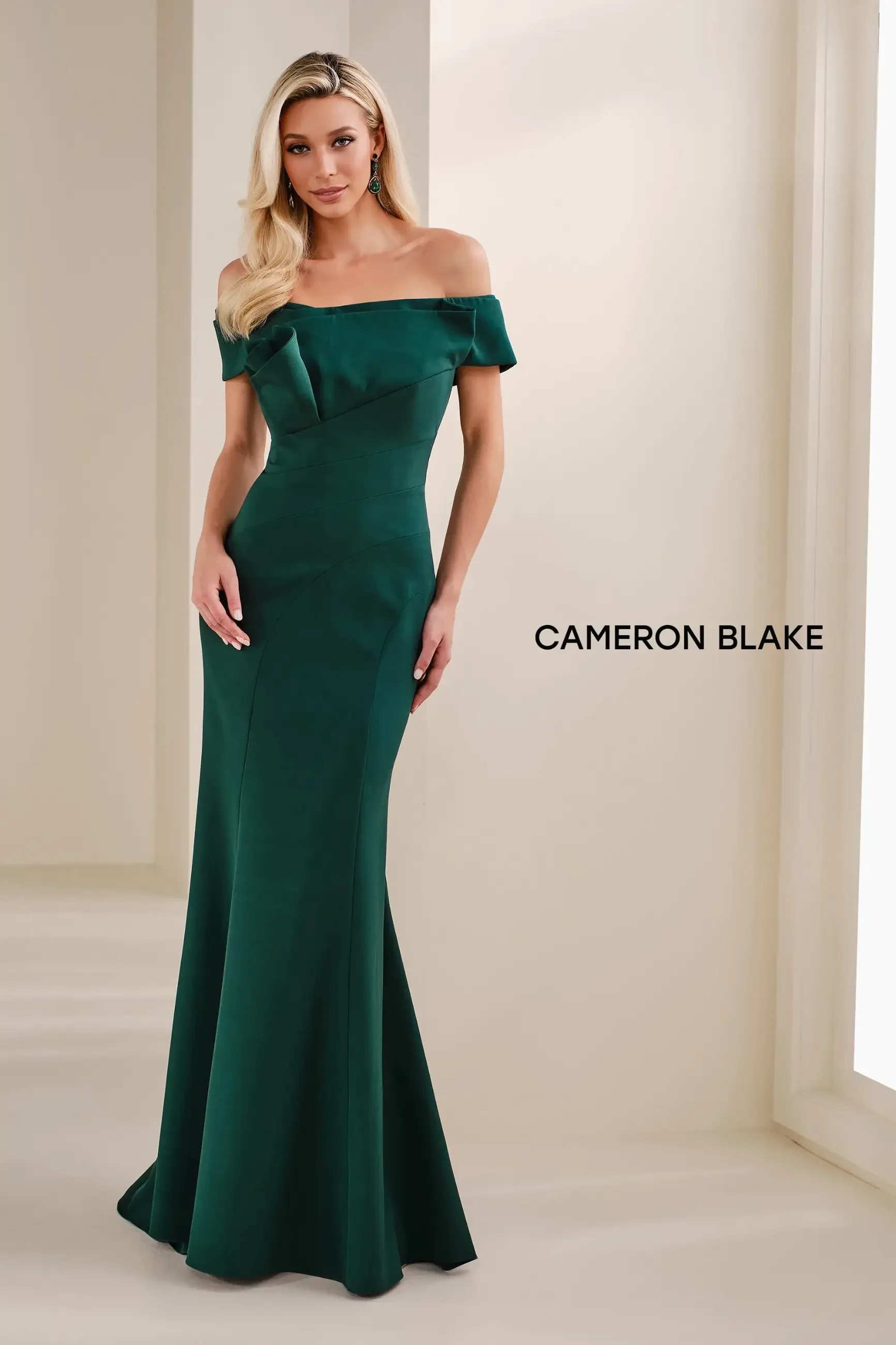 Model is wearing a Cameron Blake CB905 crepe mermaid gown in evergreen with an asymmetric couture neckline and matching shawl.