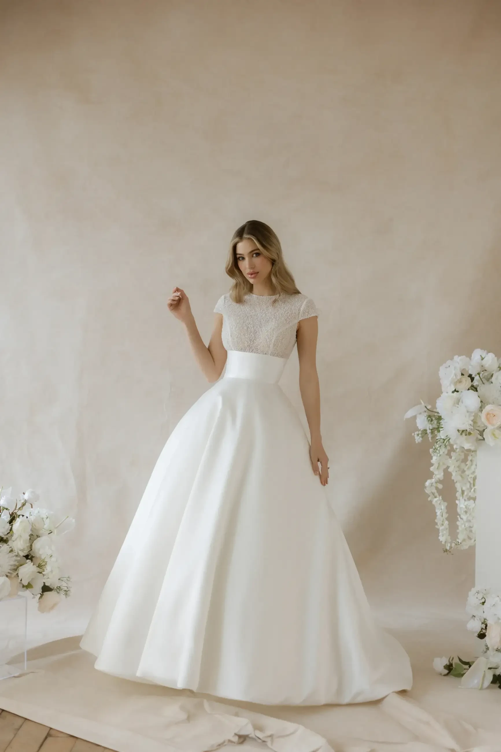 model is wearing an a-line cap sleeve wedding dress