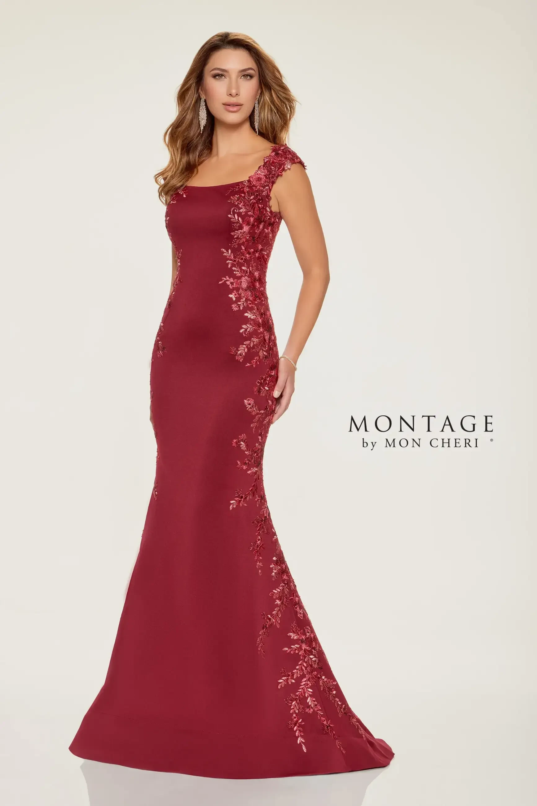 Model is wearing a fit and flare lace gown with a bateau neckline and delicate cap sleeves.
