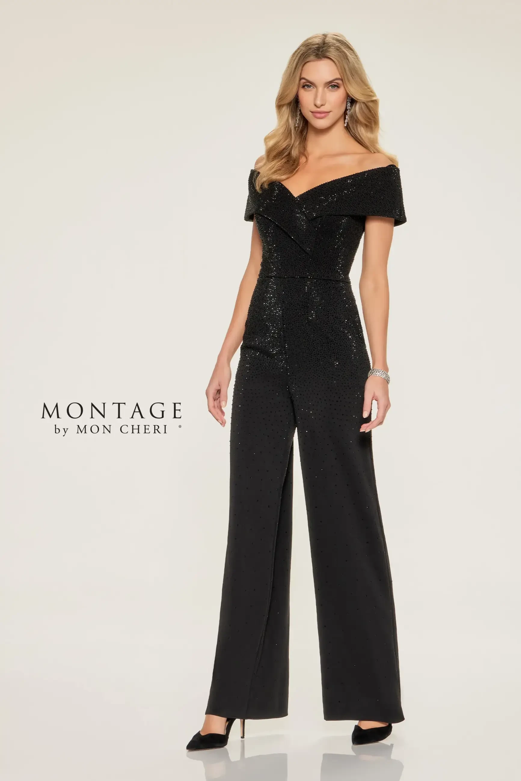 Model is wearing a shimmering off-the-shoulder jumpsuit with wide-leg pants and stone embellishments.